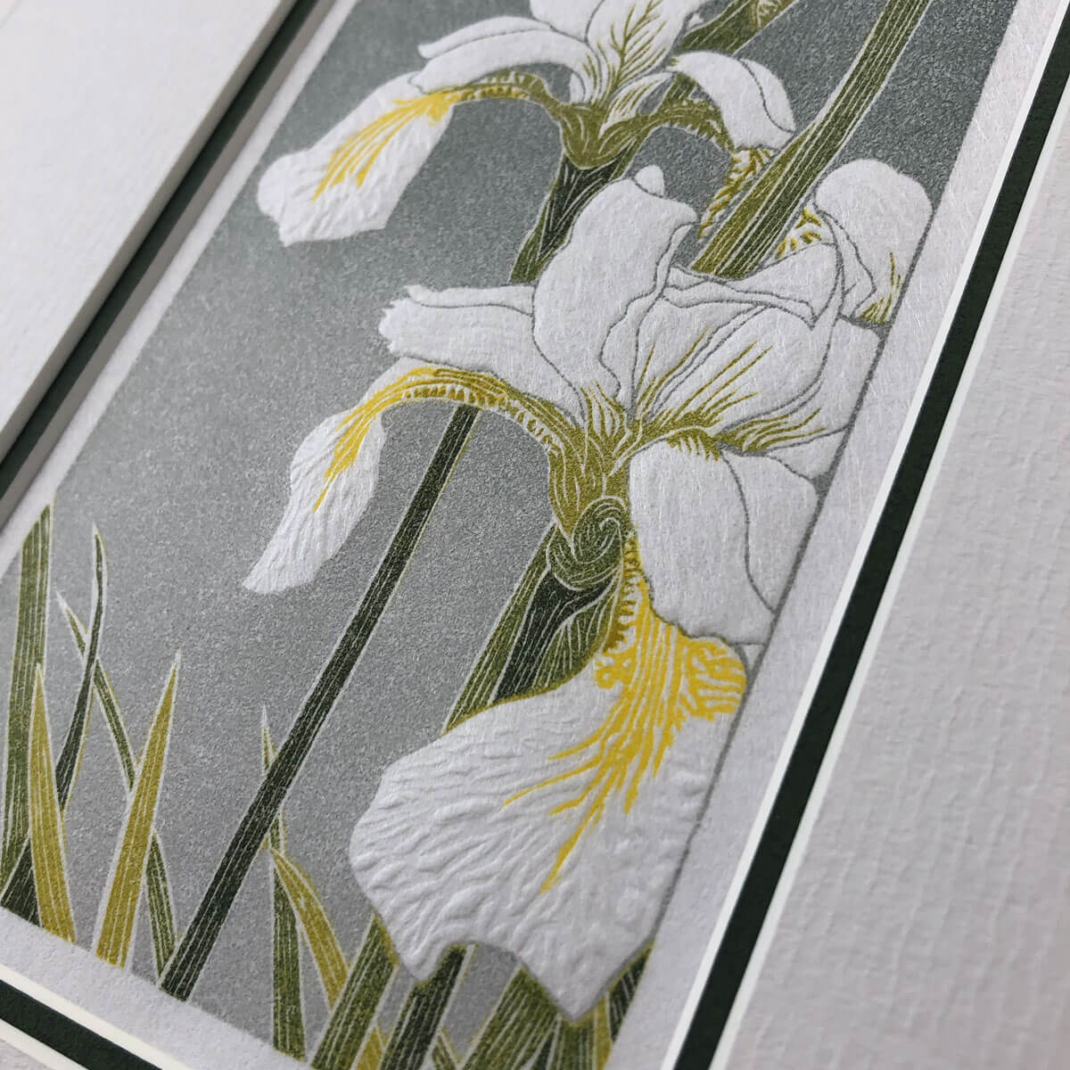 handmade linocut print of white iris flowers against a grade grey background