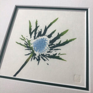 handmade woodblock print of a single blue purple eryngium, or sea holly, flowerhead against a plain pale background