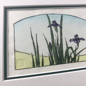 handmade woodblock print of purple iris flowers and foliage with green ground and pale blue sky