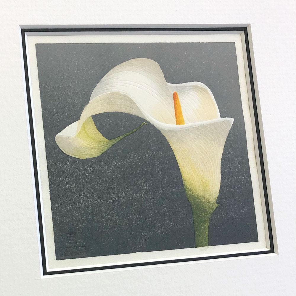 hand made woodblock print of white arum lily against a dark grey background